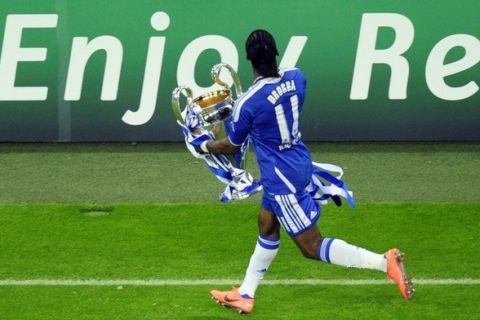 Chelsea's Ivorian forward Didier Drogba runs with the trophy after the UEFA Champions League final football match between FC Bayern Muenchen and Chelsea FC on May 19, 2012 at the Fussball Arena stadium in Munich. Chelsea beat Bayern Munich 4-3 on penalties to win the Champions League.    AFP PHOTO / JOHN MACDOUGALL        (Photo credit should read JOHN MACDOUGALL/AFP/GettyImages)