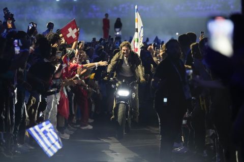 Tom Cruise rides a motorbike with the Olympic flag attached during the 2024 Summer Olympics closing ceremony at the Stade de France, Sunday, Aug. 11, 2024, in Saint-Denis, France. (AP Photo/Ashley Landis)