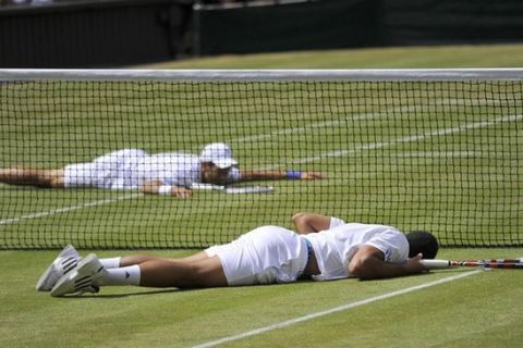 Novak Djokovic of Serbia (top) and Jo-Wilfried Tsonga of France both lay on the ground after falling as they dived to hit returns during their semi-final match at the Wimbledon tennis championships in London July 1, 2011.              REUTERS/Toby Melville (BRITAIN - Tags: SPORT TENNIS IMAGES OF THE DAY)