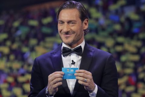 Italy's former soccer player Francesco Totti holds up the name Italy during the draw for the UEFA Euro 2020 soccer tournament finals in Bucharest, Romania, Saturday, Nov. 30, 2019. (AP Photo/Vadim Ghirda)