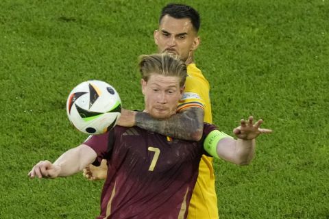 Belgium's Kevin De Bruyne , front, vies for the ball with Romania's Marius Marin during a Group E match between Belgium and Romania at the Euro 2024 soccer tournament in Cologne, Germany, Saturday, June 22, 2024. (AP Photo/Frank Augstein)