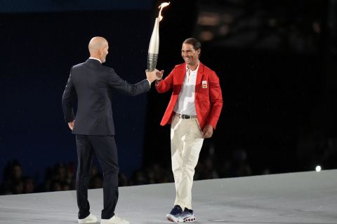 Zinedine Zidane hands the torch over to Rafael Nadal, right, in Paris, France, during the opening ceremony of the 2024 Summer Olympics, Friday, July 26, 2024. (AP Photo/Natacha Pisarenko)