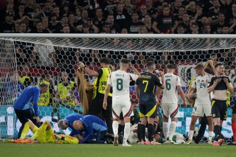 Scotland's goalkeeper Angus Gunn, down, and Hungary's Barnabas Varga get medical treatment after colliding during a Group A match between Scotland and Hungary at the Euro 2024 soccer tournament in Stuttgart, Germany, Sunday, June 23, 2024. (AP Photo/Matthias Schrader)