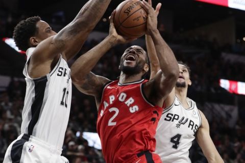 Toronto Raptors forward Kawhi Leonard (2) is blocked as he drives to the basket against San Antonio Spurs guard DeMar DeRozan (10) and guard Derrick White (4) during the first half of an NBA basketball game, Thursday, Jan. 3, 2019, in San Antonio. (AP Photo/Eric Gay)