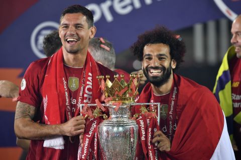 Liverpool's Dejan Lovren and Liverpool's Mohamed Salah celebrate with the English Premier League trophy aloft after it was presented following the Premier League soccer match between Liverpool and Chelsea at Anfield stadium in Liverpool, England, Wednesday, July 22, 2020. (Paul Ellis, Pool via AP)