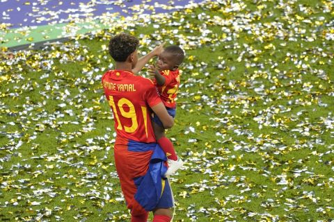 Spain's Lamine Yamal holds a baby after the final match between Spain and England at the Euro 2024 soccer tournament in Berlin, Germany, Sunday, July 14, 2024. (AP Photo/Andreea Alexandru)