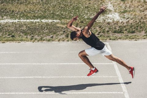 high angle view of male sprinter taking off from low start on running track