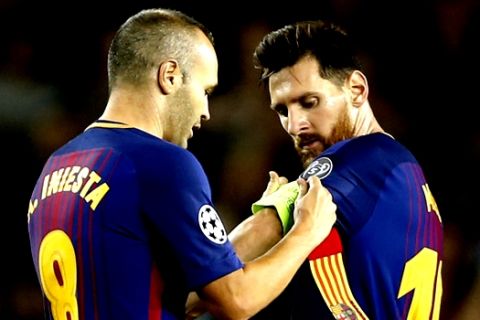 Barcelona's Andres Iniesta hands over the captain's armband to Lionel Messi during a Champions League group D soccer match between FC Barcelona and Juventus at the Camp Nou stadium in Barcelona, Spain, Tuesday, Sept. 12, 2017. (AP Photo/Francisco Seco)