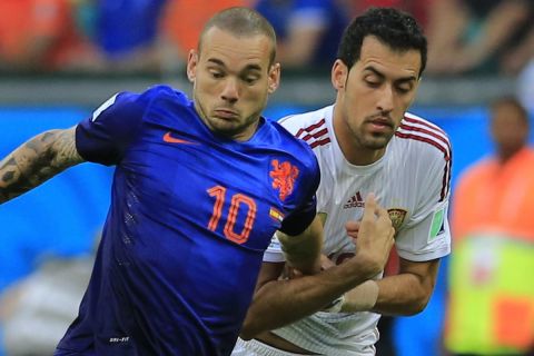 Netherlands' Wesley Sneijder, left, is challenged by Spain's Sergio Busquets during the group B World Cup soccer match between Spain and the Netherlands at the Arena Ponte Nova in Salvador, Brazil, Friday, June 13, 2014. (AP Photo/Bernat Armangue)