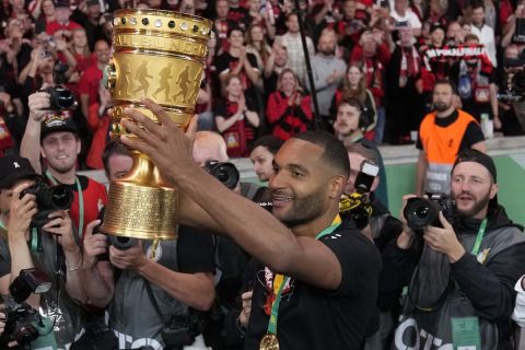 Leverkusen's Jonathan Tah lifts the trophy after the German Soccer Cup final match between 1. FC Kaiserslautern and Bayer Leverkusen at the Olympic Stadium in Berlin, Germany, Saturday, May 25, 2024. (AP Photo/Matthias Schrader)