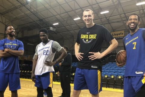 In this Dec. 4, 2018 photo, from left, Santa Cruz Warriors coach Aaron Miles, guard Will Cherry, Alen Smailagic and Darius Morris talk after their basketball practice in Santa Cruz, Calif. As the Santa Cruz Warriors huddled together after practice, Darius Morris gave a quick recap of his adventure to the Arizona desert a day earlier to interview with the Suns. Phoenix needed a point guard with Devin Booker's hamstring injury, and Morris was in the mix. Coach Aaron Miles, who so wishes he were still playing, had to stand in leading the offense given Morris' absence. Such is life in the topsy-turvy, changing-by-the-day G League, when Golden State or another club might come calling at a moment's notice to swipe a top player for promotion to the NBA. (AP Photo/Janie McCauley)