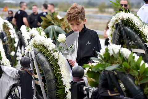 Ένα παιδί αφήνει λευκό τριαντάφυλλο στο ετήσιο μνημόσυνο για τους οπαδούς του ΠΑΟΚ στα Τέμπη