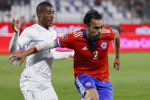 Uruguay's Nicolás de la Cruz, left, and Chile's Gabriel Suazo vie for the ball during a qualifying soccer match for the FIFA World Cup Qatar 2022 at San Carlos de Apoquindo stadium in Santiago, Chile, Tuesday, March 29, 2022. (Alberto Valdes/Pool Via AP)