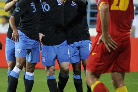 England's Wayne Rooney (C) surrounded with his co-players celebrates after scoring a goal as Montenegrin Miodrag Dzudovic (R) looks dissappointed during their Euro 2012 group G qualifying football match against Montenegro in Podgorica, on October 7, 2011.     AFP PHOTO / HRVOJE POLAN (Photo credit should read HRVOJE POLAN/AFP/Getty Images)