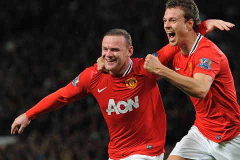 Manchester United's English forward Wayne Rooney (L) celebrates with Manchester United's Northern Irish defender Jonny Evans after scoring the opening goal against Fulham on March 26 2012 during an English Premier League football match at Old Trafford in Manchester, northwest England. AFP PHOTO/ANDREW YATES
RESTRICTED TO EDITORIAL USE. No use with unauthorized audio, video, data, fixture lists, club/league logos or live services. Online in-match use limited to 45 images, no video emulation. No use in betting, games or single club/league/player publications. (Photo credit should read ANDREW YATES/AFP/Getty Images)