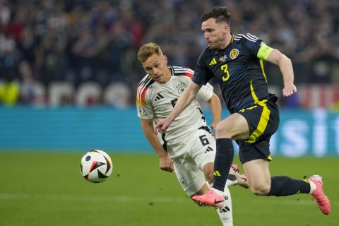 Scotland's Andrew Robertson, front, duels for the ball with Germany's Joshua Kimmich during a Group A match between Germany and Scotland at the Euro 2024 soccer tournament in Munich, Germany, Friday, June 14, 2024. (AP Photo/Antonio Calanni)