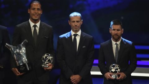 Dutch soccer player Virgil van Dijk of Liverpool, left, holds the award of men's player of the year 2018/19 as he pose with UEFA President Aleksander Ceferin, center, and Barcelona's soccer player Lionel Messi during the group stage draw at the Grimaldi Forum, in Monaco, Thursday, Aug. 29, 2019. (AP Photo/Daniel Cole)