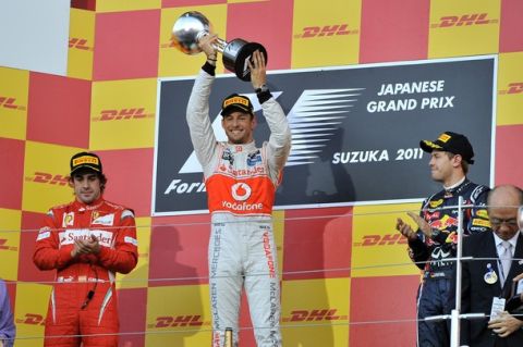 McLaren-Mercedes driver Jenson Button (C) of Britain raises the winner's trophy as second-placed Ferrari driver Fernando Alonso of Spain (L) and third-placed Red Bull-Renault driver Sebastian Vettel of Germany (R) celebrate on the podium of the Formula One Japanese Grand Prix at Suzuka on October 9, 2011. Vettel, 24, became Formula One's youngest back-to-back world champion on October 9 when he finished third in the Japanese Grand Prix behind Button and  Alonso.  AFP PHOTO/JUNG YEON-JE (Photo credit should read JUNG YEON-JE/AFP/Getty Images)