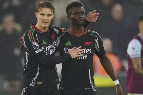 Arsenal's Martin Odegaard, left, celebrates with Arsenal's Bukayo Saka after scoring his side's third goal during the English Premier League soccer match between West Ham and Arsenal at the London Stadium in London, Saturday, Nov. 30, 2024. (AP Photo/Dave Shopland)