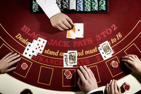 A group of people playing Black Jack on a red casino table. Studio shoot seen from above.