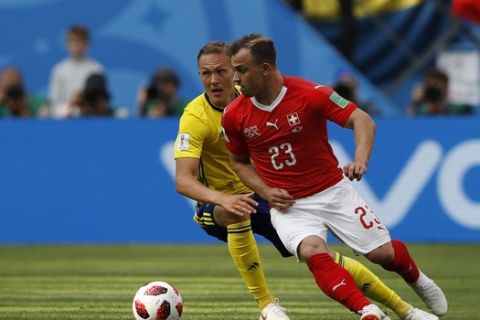 Switzerland's Xherdan Shaqiri, right, tussles for the ball with Sweden's Ludwig Augustinsson during the round of 16 match between Switzerland and Sweden at the 2018 soccer World Cup in the St. Petersburg Stadium, in St. Petersburg, Russia, Tuesday, July 3, 2018. (AP Photo/Darko Bandic)