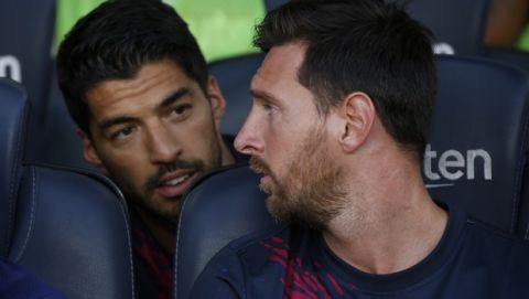 Barcelona forward Lionel Messi, right, talks with his teammate Luis Suarez from the bench prior of the Joan Gamper trophy soccer match between FC Barcelona and Arsenal at the Camp Nou stadium in Barcelona, Spain, Sunday, Aug. 4, 2019. (AP Photo/Joan Monfort)