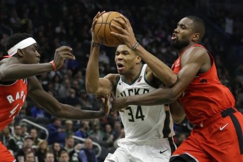 Milwaukee Bucks' Giannis Antetokounmpo, middle, drives to the basket between Toronto Raptors' Pascal Siakam, left, and Serge Ibaka, right, during the second half of an NBA basketball game, Saturday, Jan. 5, 2019, in Milwaukee. The Raptors won 123-116. (AP Photo/Aaron Gash)