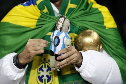 A Brazil fan in the stands with a voodoo doll of Lionel Messi and a replica of the world cup trophy