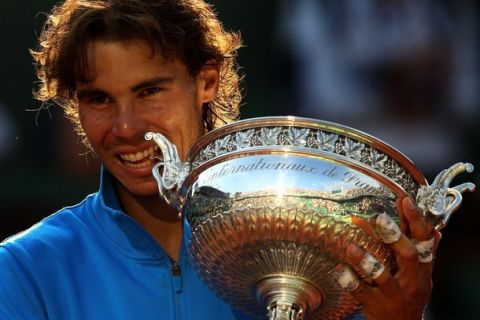 PARIS, FRANCE - JUNE 05:  Champion Rafael Nadal of Spain bites the trophy following his record equalling sixth victory during the men's singles final match between Rafael Nadal of Spain and Roger Federer of Switzerland on day fifteen of the French Open at Roland Garros on June 5, 2011 in Paris, France.  (Photo by Clive Brunskill/Getty Images)