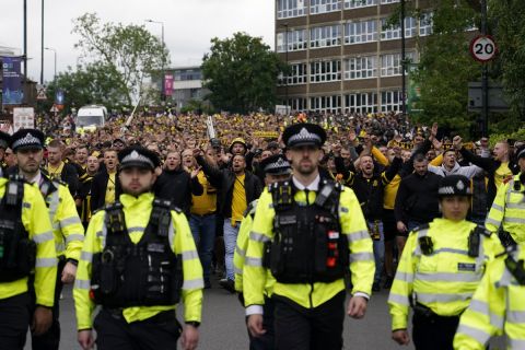 A line of police officers escort Dortmund supporters as they arrive for the Champions League final soccer match between Borussia Dortmund and Real Madrid at Wembley stadium in London, Saturday, June 1, 2024. (AP Photo/Alberto Pezzali)