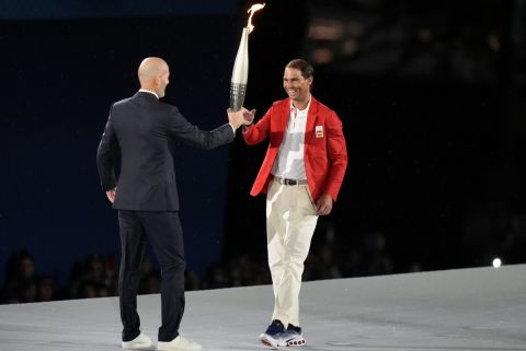 Zinedine Zidane hands the torch over to Rafael Nadal, right, in Paris, France, during the opening ceremony of the 2024 Summer Olympics, Friday, July 26, 2024. (AP Photo/Natacha Pisarenko)