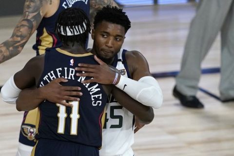 Utah Jazz's Donovan Mitchell (45) and New Orleans Pelicans' Jrue Holiday (11) hug following an NBA basketball game Thursday, July 30, 2020, in Lake Buena Vista, Fla. The Jazz won 106-104. (AP Photo/Ashley Landis, Pool)