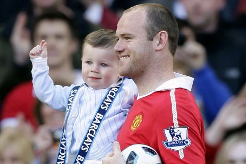 Manchester United's Wayne Rooney is pictured with his son Kai, left, after celebrating with the English Premier League trophy after their match against Blackpool at Old Trafford, Manchester, England, Sunday, May 22, 2011. Manchester United celebrated winning the league for a 19th time beating Liverpool's long standing record. (AP Photo/Jon Super). NO INTERNET/MOBILE USAGE WITHOUT FOOTBALL ASSOCIATION PREMIER LEAGUE(FAPL)LICENCE. CALL +44 (0) 20 7864 9121 or EMAIL info@football-dataco.com FOR DETAILS