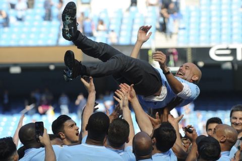 Manchester City players lift manager Josep Guardiola during celebrations for winning the English Premier League title after the soccer match between Manchester City and Huddersfield Town at Etihad stadium in Manchester, England, Sunday, May 6, 2018. (AP Photo/Rui Vieira)