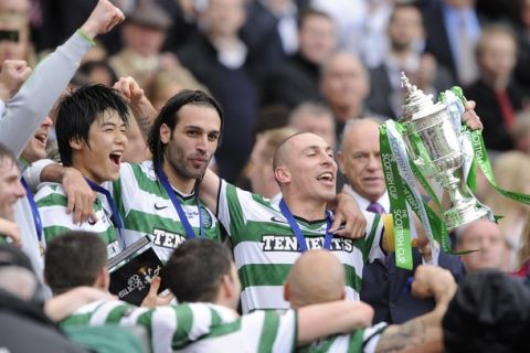 Celtic's captain Scott Brown (R) lifts the trophy with Georgios Samaras and Ki Sung-Yueng (L) following their victory over Motherwell in their Scottish Cup final soccer match at Hampden Park, Glasgow, Scotland, May 21, 2011. REUTERS/Russell Cheyne (BRITAIN - Tags: SPORT SOCCER)