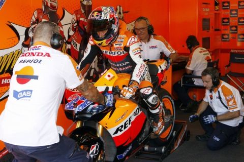 Honda MotoGP rider Casey Stoner (C) of Australia sits on his motorcycle in his garage while his crew prepares to push him out during qualifications for the Indianapolis Grand Prix in Indianapolis August 27, 2011.   REUTERS/Brent Smith (UNITED STATES - Tags: SPORT MOTORSPORT)