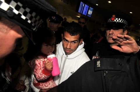 Police escort Manchester City's Argentinian footballer Carlos Tevez (C) as he arrives with his family at Manchester airport in north-west England, on February 14, 2012. Carlos Tevez arrived back in England Tuesday accusing Manchester City manager Roberto Mancini of treating him "like a dog" in the incident that led to his exile from the Premier League leaders. Tevez hasn't played for City since that September 27 match in Germany but is due to return to Eastlands on Tuesday in a bid to revive a career that has effectively been suspended for more than three months. AFP PHOTO/BEN STANSALL (Photo credit should read BEN STANSALL/AFP/Getty Images)