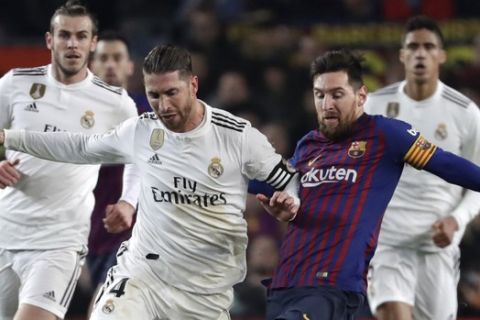 Real defender Sergio Ramos, center left, and Barcelona forward Lionel Messi vie for the ball during the Copa del Rey semifinal first leg soccer match between FC Barcelona and Real Madrid at the Camp Nou stadium in Barcelona, Spain, Wednesday Feb. 6, 2019. (AP Photo/Emilio Morenatti)