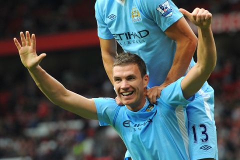 Manchester City's Bosnian striker Edin Dzeko celebrates with Manchester City's Serbian defender Aleksandar Kolarov (up) after scoring their sixth goal during the English Premier League football match between Manchester United and Manchester City at Old Trafford in Manchester, north-west England on October 23, 2011. AFP PHOTO/ANDREW YATES

RESTRICTED TO EDITORIAL USE. No use with unauthorized audio, video, data, fixture lists, club/league logos or live services. Online in-match use limited to 45 images, no video emulation. No use in betting, games or single club/league/player publications (Photo credit should read ANDREW YATES/AFP/Getty Images)