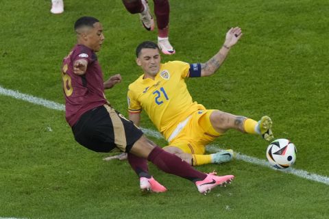 Belgium's Youri Tielemans, left, scores his side's opening goal past Romania's Nicolae Stanciu during a Group E match between Belgium and Romania at the Euro 2024 soccer tournament in Cologne, Germany, Saturday, June 22, 2024. (AP Photo/Frank Augstein)