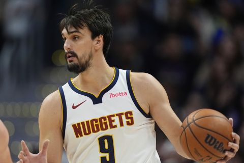 Denver Nuggets forward Dario Saric, right, looks to pass the ball as Phoenix Suns center Frank Kaminsky defends in the second half of an NBA preseason game Sunday, Oct. 13, 2024, in Denver. (AP Photo/David Zalubowski)