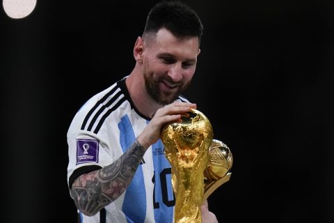 FILE - Argentina's Lionel Messi holds best player of the tournament trophy as he touches the World Cup trophy after the World Cup final soccer match between Argentina and France at the Lusail Stadium in Lusail, Qatar, Sunday, Dec. 18, 2022. (AP Photo/Petr David Josek, File)