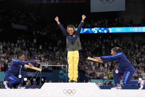 Silver medalist Simone Biles, of the United States, left, and bronze medalist Jordan Chiles, of the United States, right, bow to gold medalist Rebeca Andrade, of Brazil, during the medal ceremony for the women's artistic gymnastics individual floor finals at Bercy Arena at the 2024 Summer Olympics, Monday, Aug. 5, 2024, in Paris, France. (AP Photo/Abbie Parr)