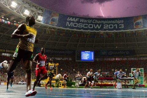 Jamaica's Usain Bolt (L) wins the100 metres final at the 2013 IAAF World Championships at the Luzhniki stadium in Moscow on August 11, 2013 while a lightning strikes in the sky. Bolt timed a season's best 9.77 seconds, with American Justin Gatlin claiming silver in 9.85sec and Nesta Carter, also of Jamaica, taking bronze in 9.95sec. 
 AFP PHOTO / OLIVIER MORIN        (Photo credit should read OLIVIER MORIN/AFP/Getty Images)