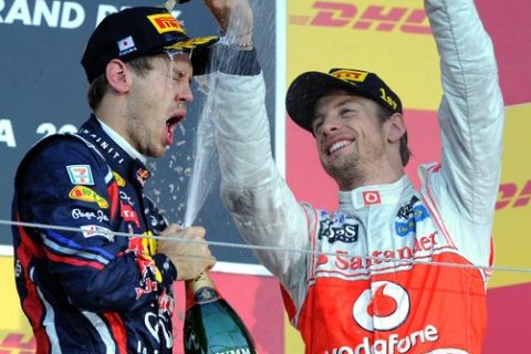 Winner McLaren-Mercedes driver Jenson Button of Britain (R) pours champagne over third-placed Red Bull-Renault driver Sebastian Vettel of Germany (L) on the podium during the award ceremony for the Formula One Japanese Grand Prix at Suzuka on October 9, 2011.  Vettel, 24, became Formula One's youngest back-to-back world champion on October 9 when he finished third in the Japanese Grand Prix.   AFP PHOTO / TOSHIFUMI KITAMURA (Photo credit should read TOSHIFUMI KITAMURA/AFP/Getty Images)