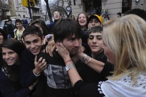 Surrounded by fans, Argentina's soccer player Lionel Messi, center, is held by an unidentified woman as he leaves a restaurant in Rosario, Argentina,  Thursday, June 2, 2011. According to witnesses at the restaurant, an alleged fan of Rosario Central, a local soccer team, attempted to attack Barcelona soccer star. Messi was not reported injured. (AP Photo/Jose Granata,Telam)