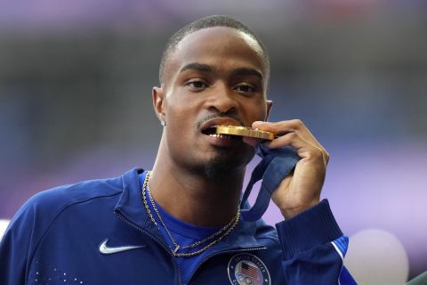 Men's 400-meter gold medalist Quincy Hall, of the United States, bites into his medal as he poses on the podium at the 2024 Summer Olympics, Thursday, Aug. 8, 2024, in Saint-Denis, France. (AP Photo/Natacha Pisarenko)