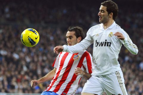 Real Madrid's Argentinian forward Gonzalo Higuain (R) vies with Atletico Madrid's Uruguayan defender Diego Godin during their Spanish league football match between Real Madrid and Atletico Madrid at the Santiago Bernabeu stadium in Madrid on November 26, 2011.  AFP PHOTO / PIERRE-PHILIPPE MARCOU (Photo credit should read PIERRE-PHILIPPE MARCOU/AFP/Getty Images)