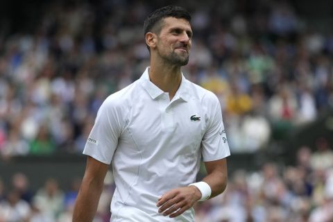 Novak Djokovic of Serbia smiles as he walks to the service line as he plays against Lorenzo Musetti of Italy during their semifinal match at the Wimbledon tennis championships in London, Friday, July 12, 2024. (AP Photo/Mosa'ab Elshamy)