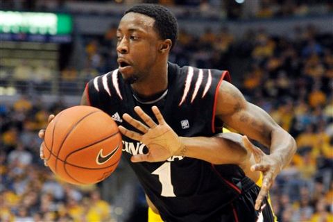 Cincinnati's Cashmere Wright (1) drives to the basket as the hand of Marquette's Todd Mayo tries to poke the ball away during the second half of an NCAA college basketball game, Saturday, Feb. 11, 2012, in Milwaukee. Marquette won 95-78. (AP Photo/Jim Prisching)